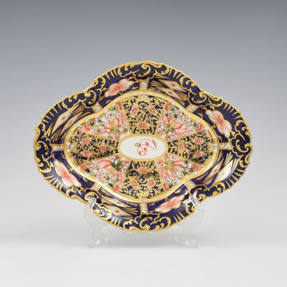 An oval antique Royal Crown Derby porcelain serving dish featuring intricate cobalt blue, coral red, and heavy gold leaf Imari pattern 6299 details with a lobed edge.