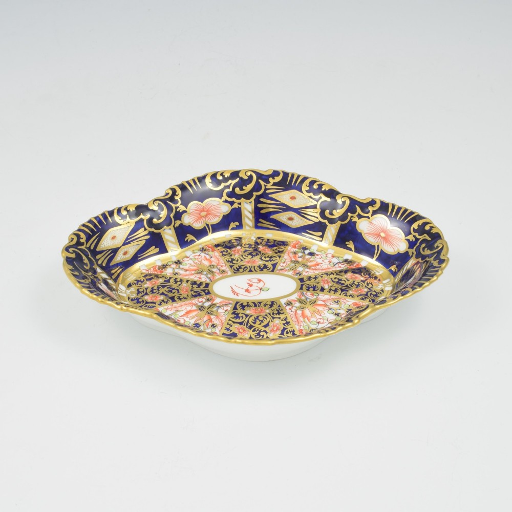 An oval antique Royal Crown Derby porcelain serving dish featuring intricate cobalt blue, coral red, and heavy gold leaf Imari pattern 6299 details with a lobed edge. View II