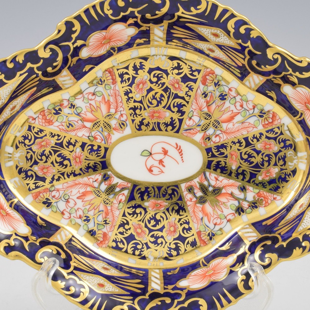 An oval antique Royal Crown Derby porcelain serving dish featuring intricate cobalt blue, coral red, and heavy gold leaf Imari pattern 6299 details with a lobed edge. View V