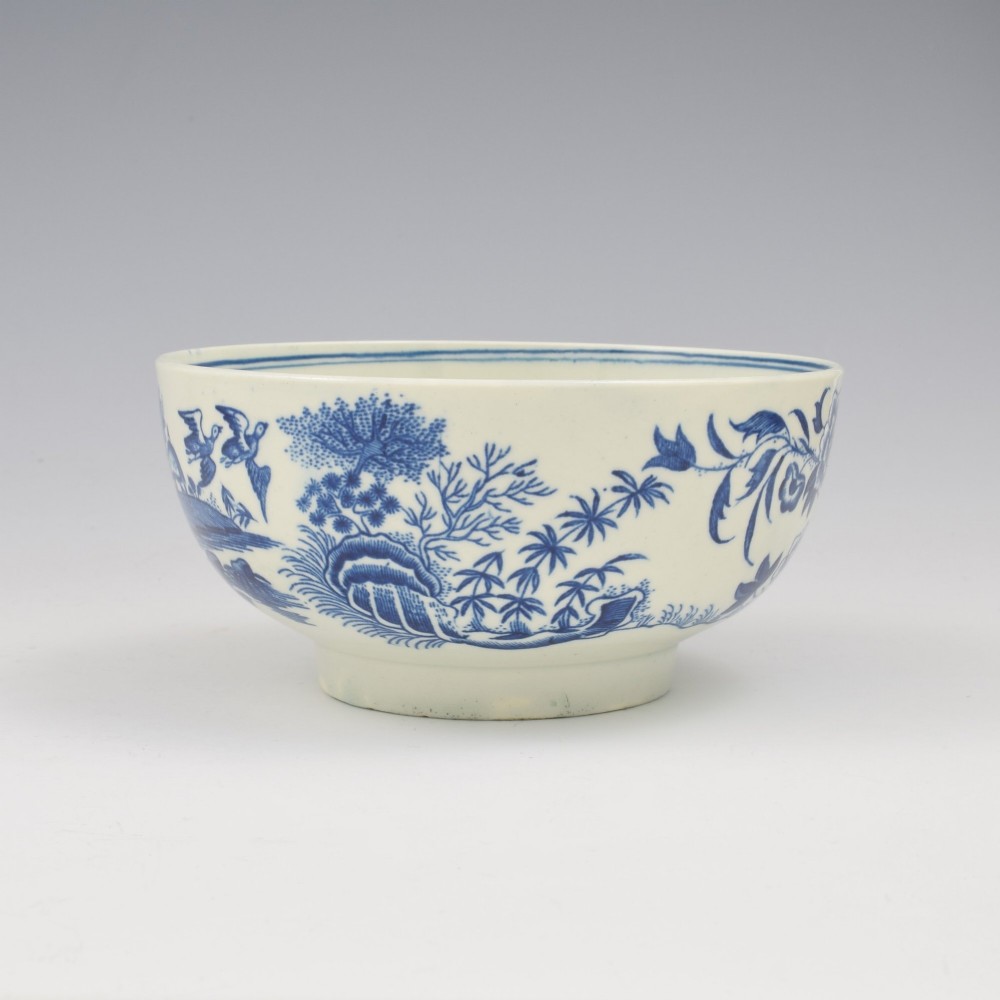 An 18th-century blue and white soft-paste porcelain slop bowl decorated with the oriental fence pattern and floral motifs. View III