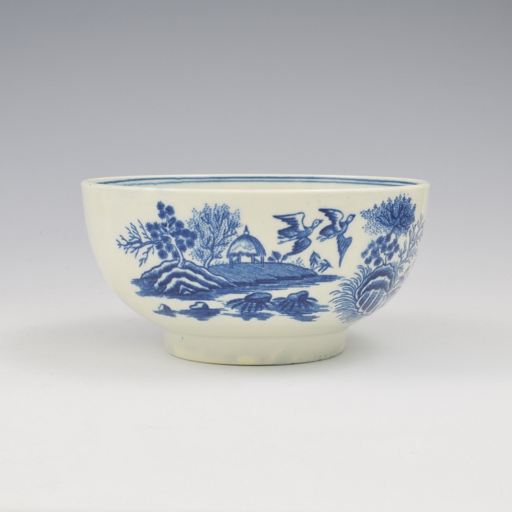 An 18th-century blue and white soft-paste porcelain slop bowl decorated with the oriental fence pattern and floral motifs. View IV