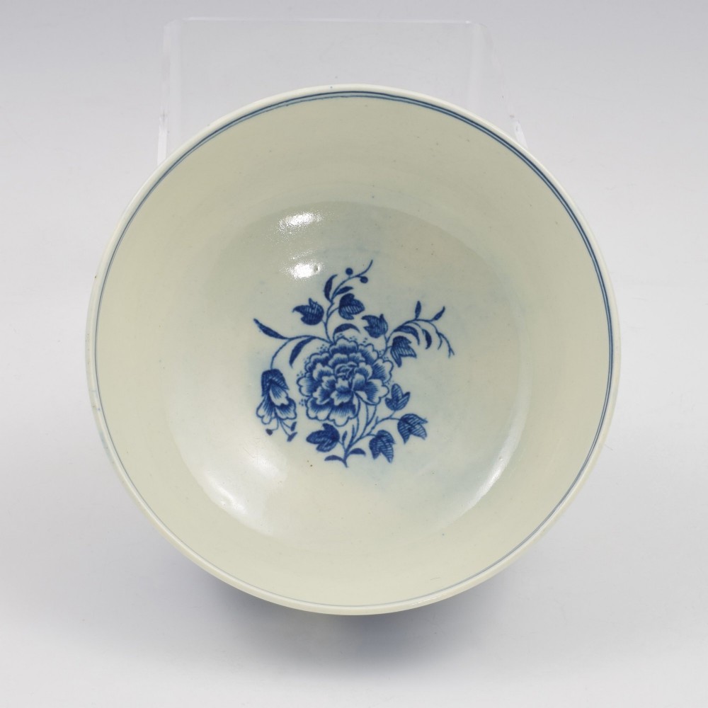 An 18th-century blue and white soft-paste porcelain slop bowl decorated with the oriental fence pattern and floral motifs. View VI