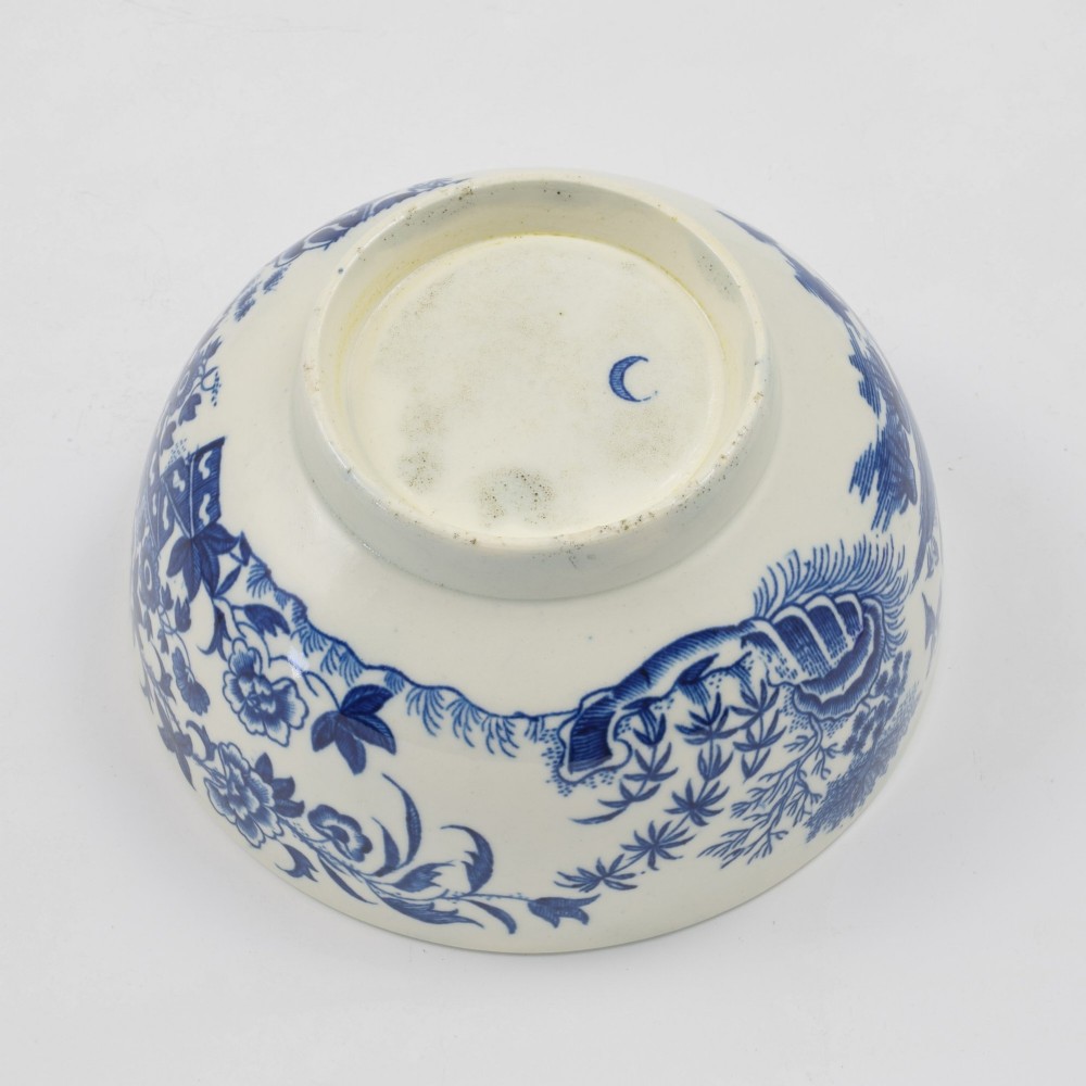 An 18th-century blue and white soft-paste porcelain slop bowl decorated with the oriental fence pattern and floral motifs. View VII