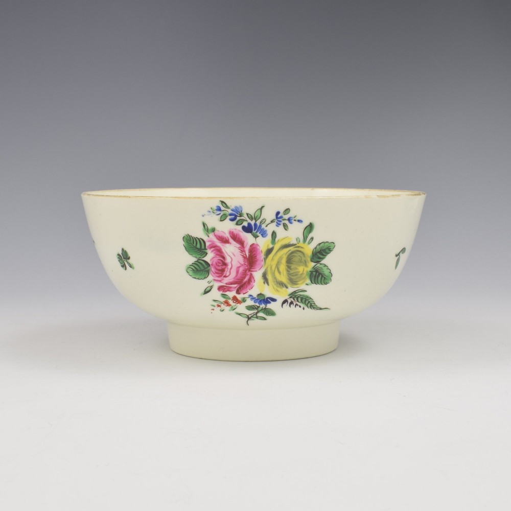 An 18th-century cream soft-paste porcelain slop bowl decorated with hand-painted floral motifs on a short foot rim.