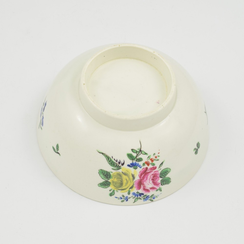 An 18th-century cream soft-paste porcelain slop bowl decorated with hand-painted floral motifs on a short foot rim. View VI