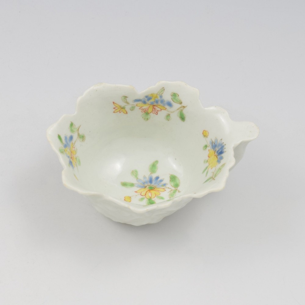 An eighteenth-century Dr Wall First Period Worcester soft-paste porcelain butter boat featuring hand-painted polychrome floral enamel sprigs and a leaf-moulded rim.