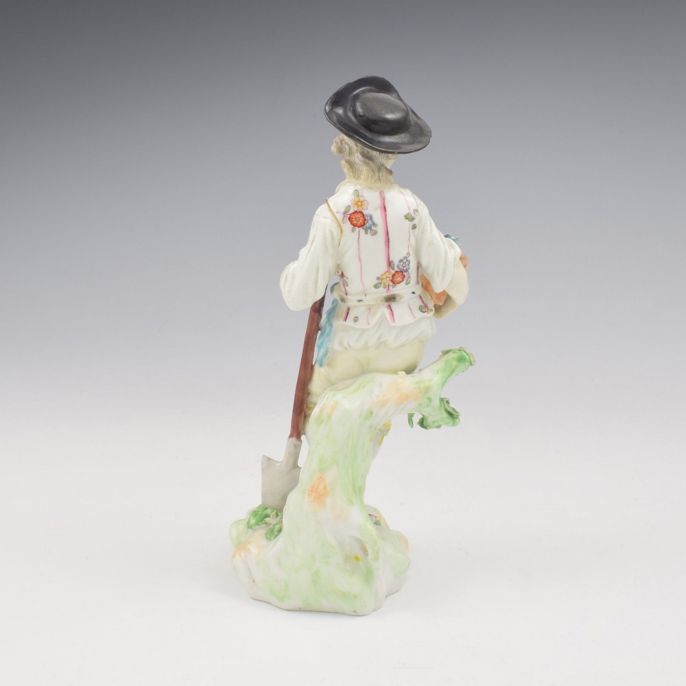 An 18th-century Derby porcelain figurine depicting a gardener holding a flower pot and leaning on a spade. View V