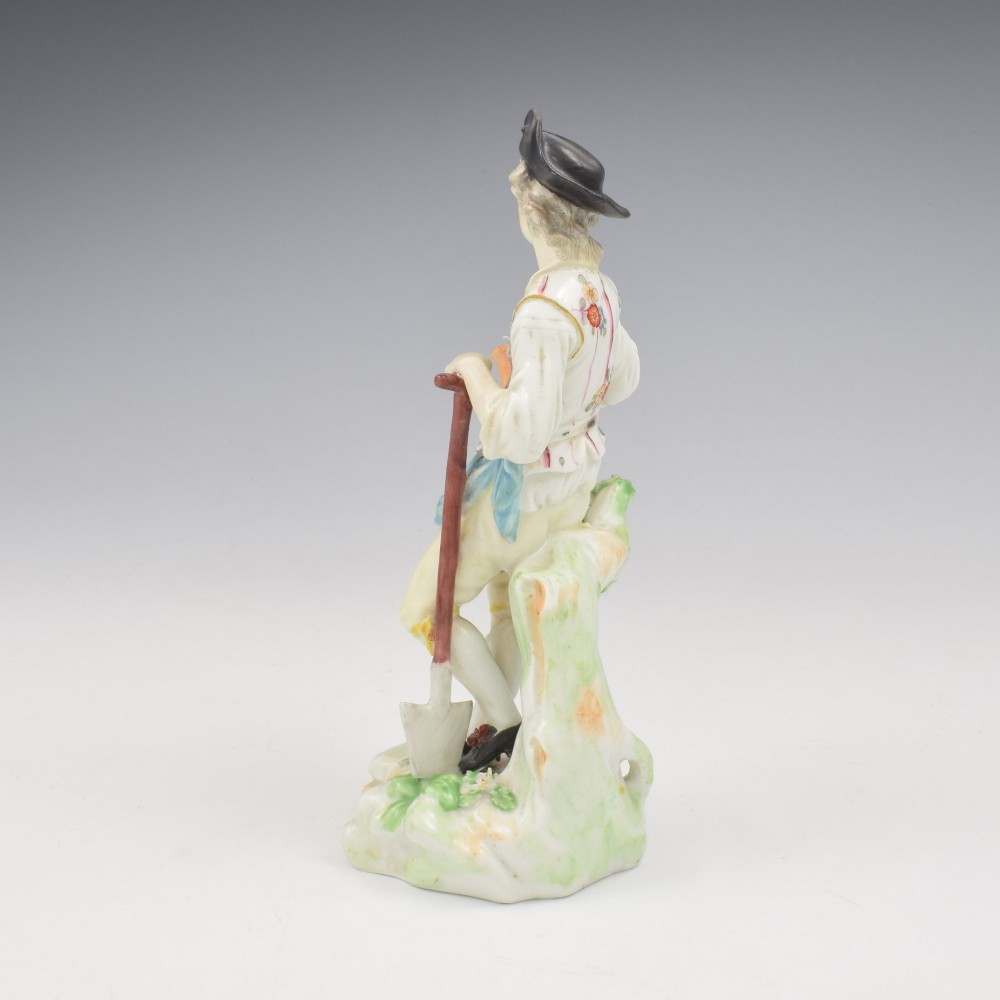 An 18th-century Derby porcelain figurine depicting a gardener holding a flower pot and leaning on a spade. View VI