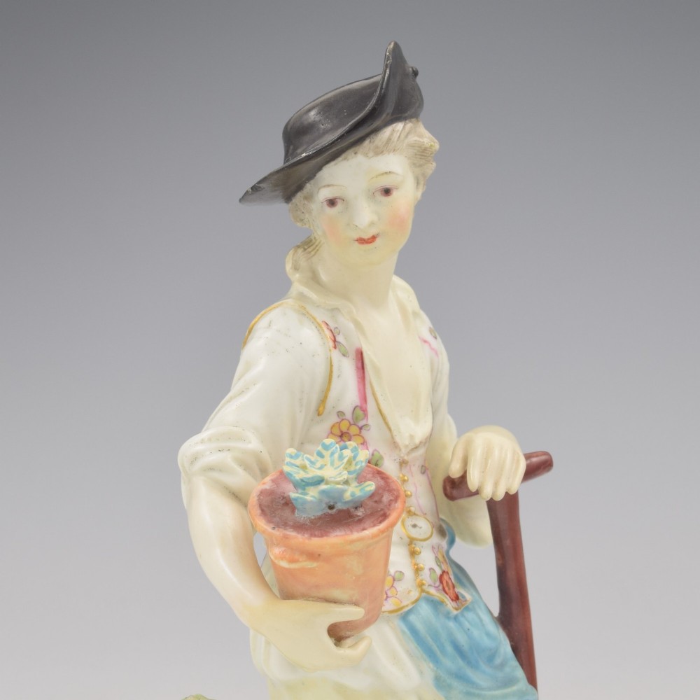 An 18th-century Derby porcelain figurine depicting a gardener holding a flower pot and leaning on a spade. View X