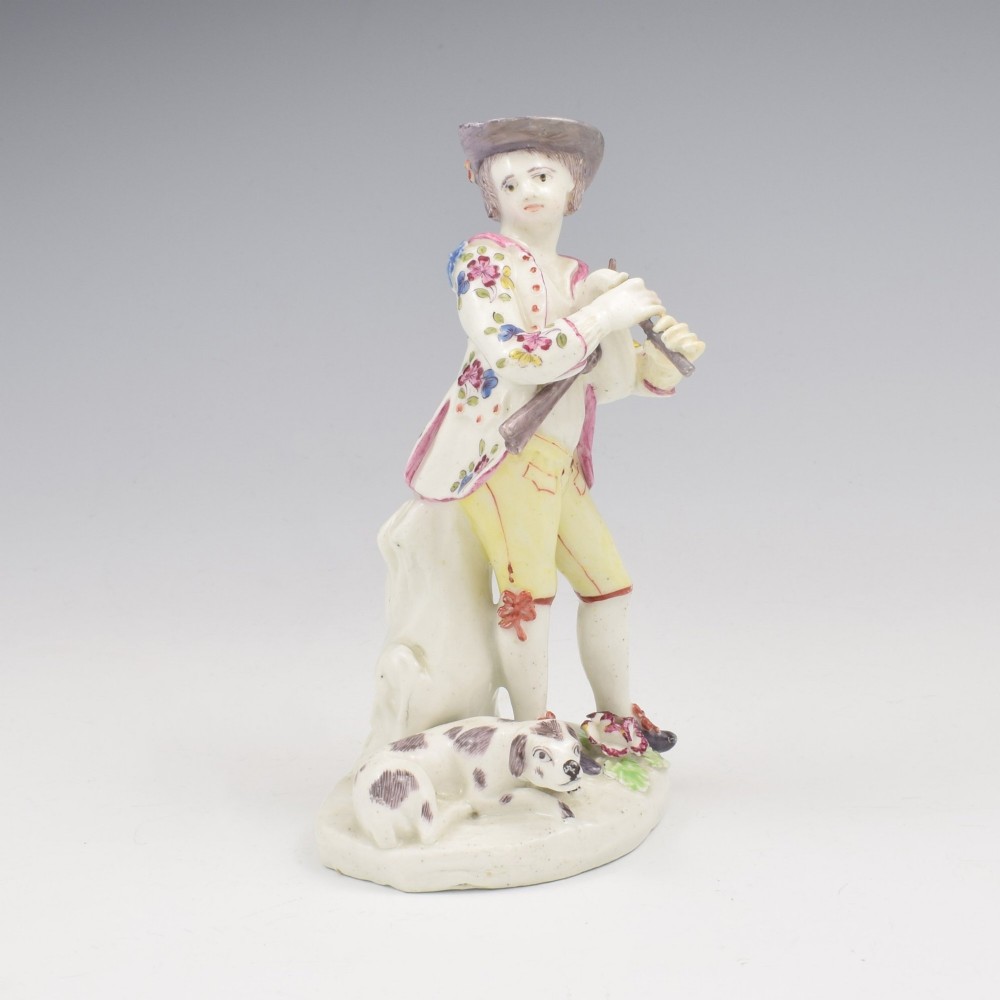 An eighteenth-century Bow porcelain figurine depicting a young shepherd playing a pipe alongside a small dog on a sculpted base. View II