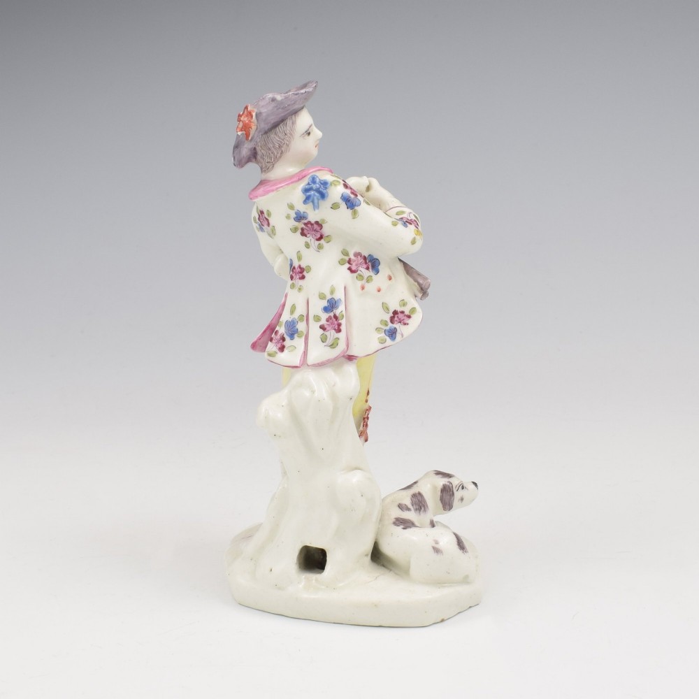 An eighteenth-century Bow porcelain figurine depicting a young shepherd playing a pipe alongside a small dog on a sculpted base. View IV