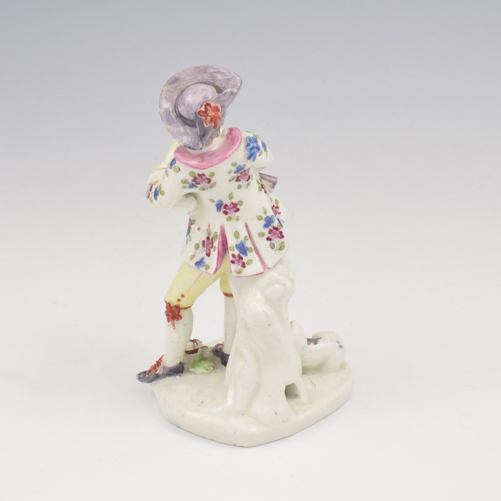 An eighteenth-century Bow porcelain figurine depicting a young shepherd playing a pipe alongside a small dog on a sculpted base. View VI