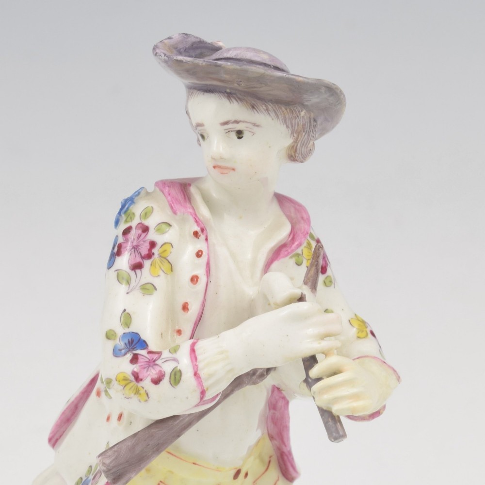 An eighteenth-century Bow porcelain figurine depicting a young shepherd playing a pipe alongside a small dog on a sculpted base. View IX