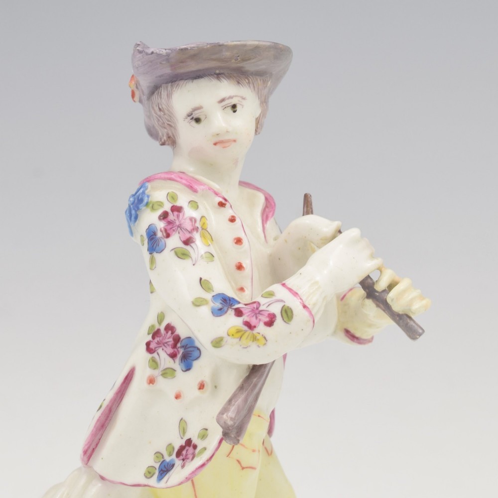 An eighteenth-century Bow porcelain figurine depicting a young shepherd playing a pipe alongside a small dog on a sculpted base. View X