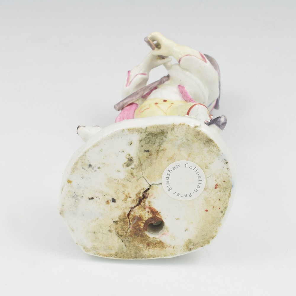 An eighteenth-century Bow porcelain figurine depicting a young shepherd playing a pipe alongside a small dog on a sculpted base. View XV