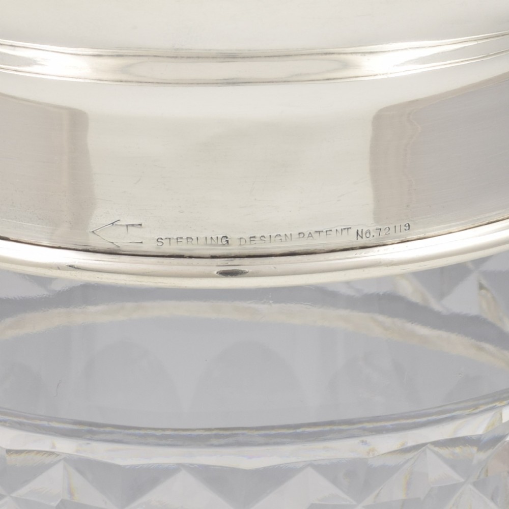 An Art Deco cocktail shaker featuring a clear cut glass body with geometric facet patterns and a polished sterling silver mount and octagonal cap. View IV