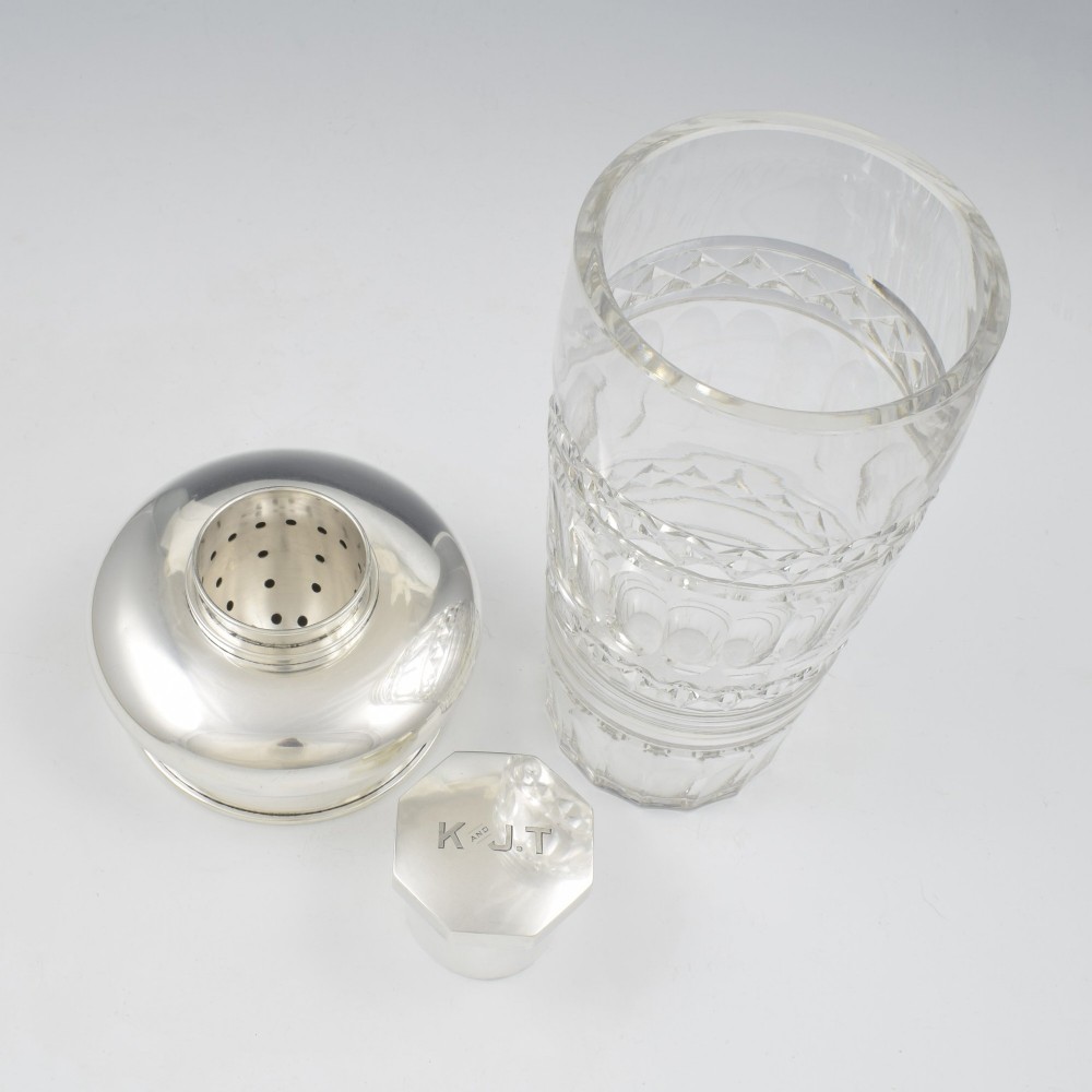 An Art Deco cocktail shaker featuring a clear cut glass body with geometric facet patterns and a polished sterling silver mount and octagonal cap. View VIII