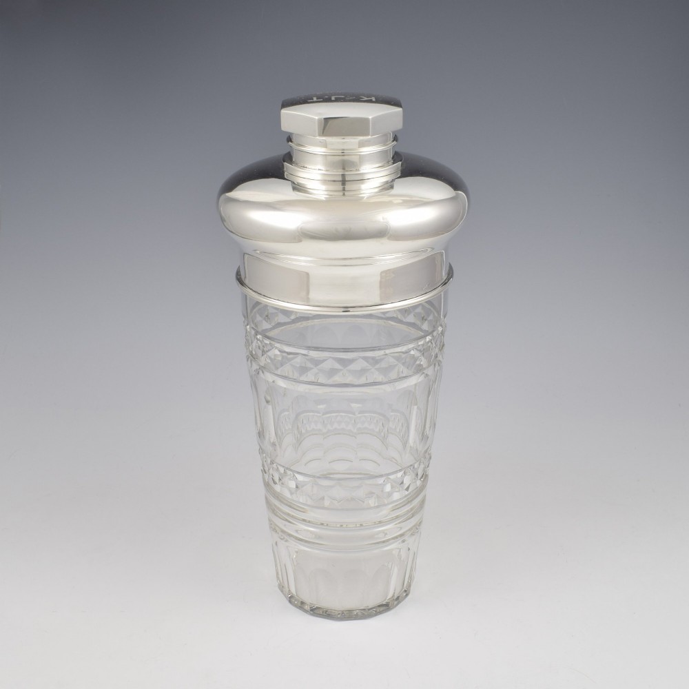 An Art Deco cocktail shaker featuring a clear cut glass body with geometric facet patterns and a polished sterling silver mount and octagonal cap. View XI