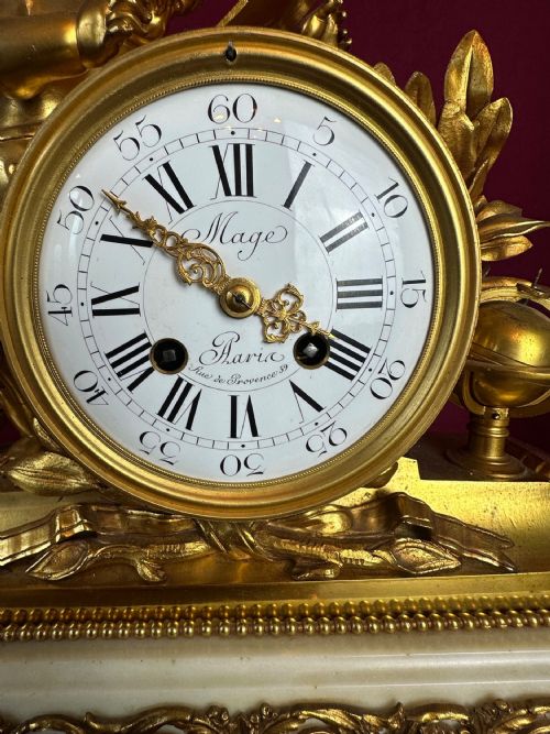 fig 1. A late 19th-century three-piece French ormolu and white marble clock garniture set featuring a central putto-adorned mantel clock flanked by matching three-light candelabra.