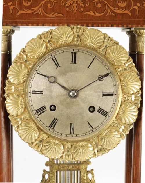fig 1. A late 19th-century French portico mantel clock crafted from dark wood with floral marquetry inlays, featuring twin columns and a decorative brass pendulum.