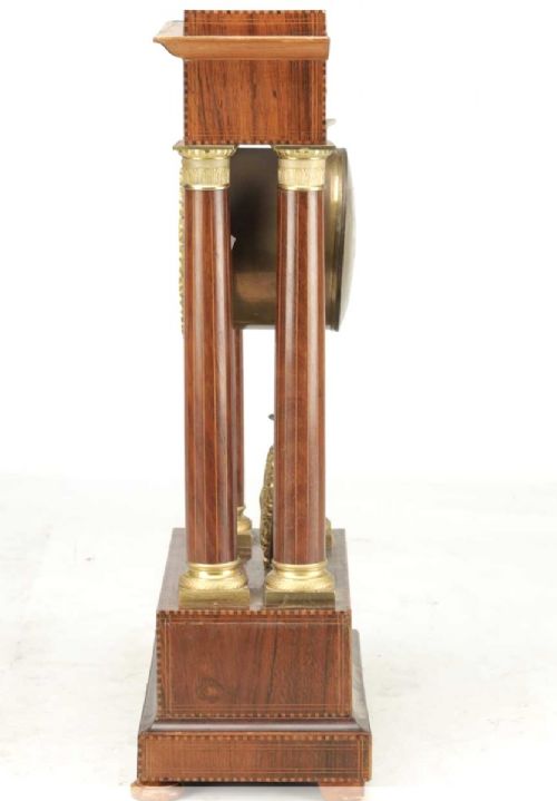 A late 19th-century French portico mantel clock crafted from dark wood with floral marquetry inlays, featuring twin columns and a decorative brass pendulum. View V