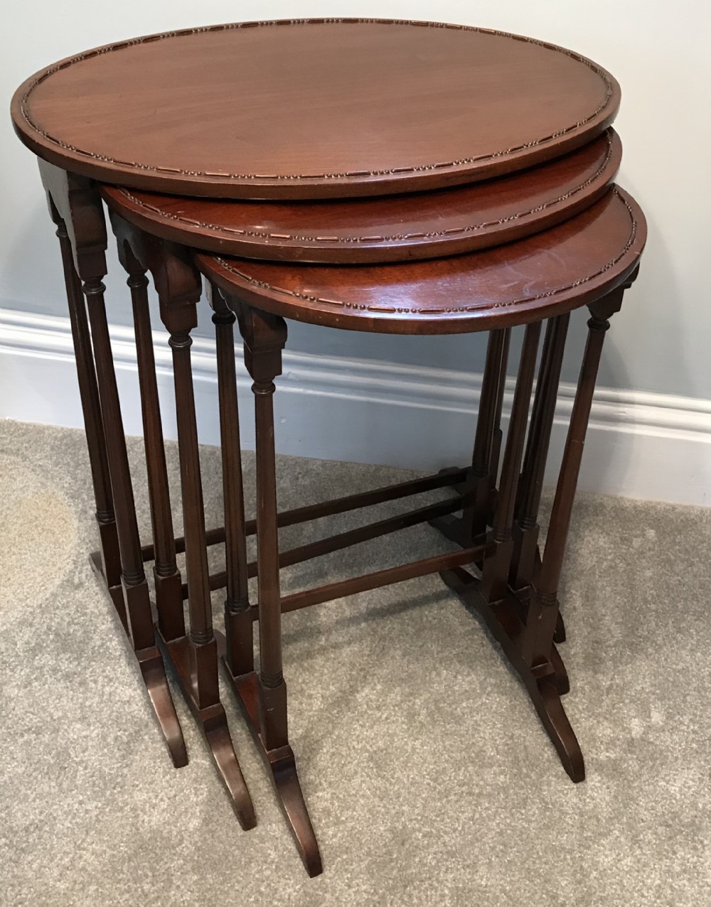 A set of three graduating oval mahogany side tables with carved beaded rims and slender turned legs.