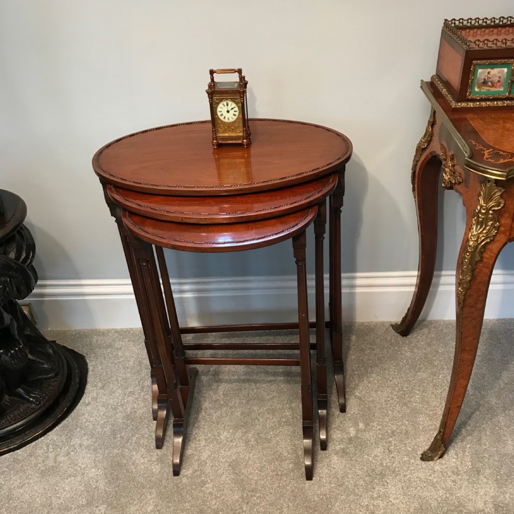 A set of three graduating oval mahogany side tables with carved beaded rims and slender turned legs. View VII