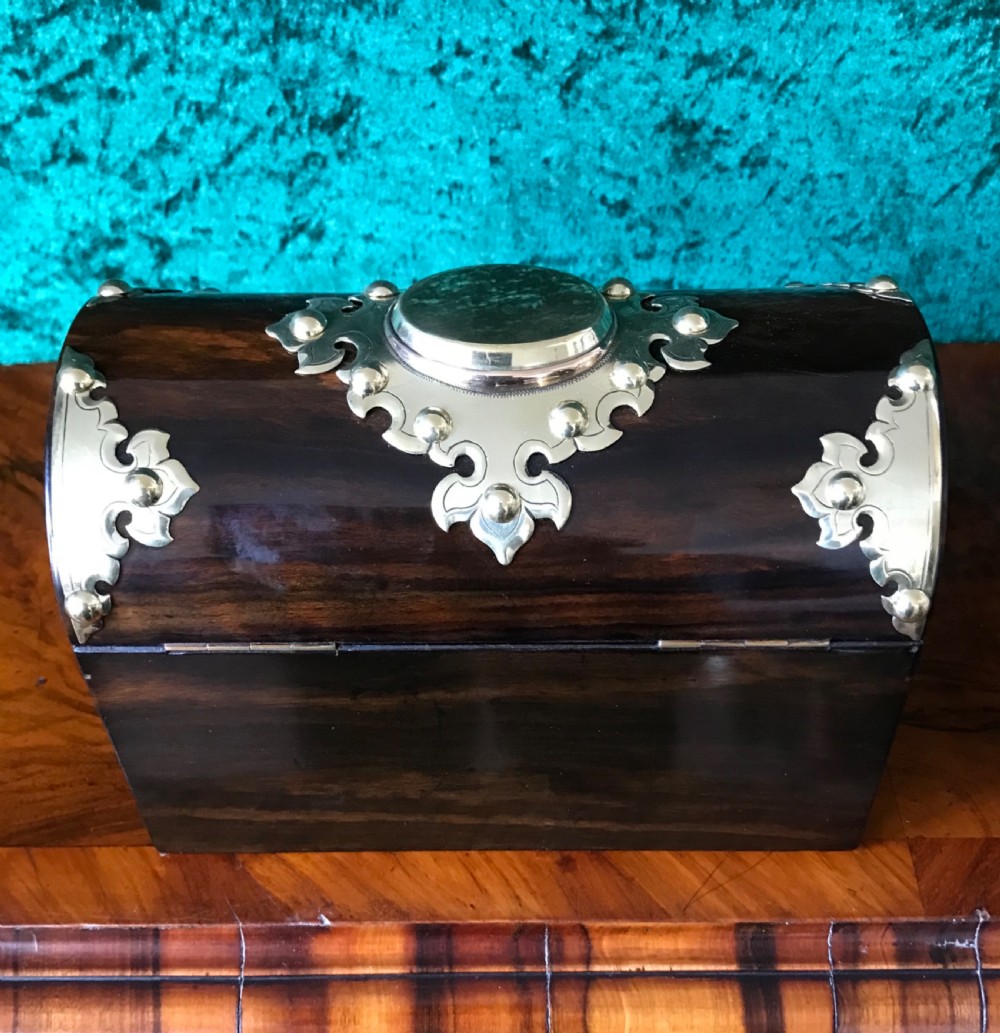 A Victorian dome-topped wooden box crafted from dark timber featuring decorative pierced brass strapwork and a key inserted in the lock. View V