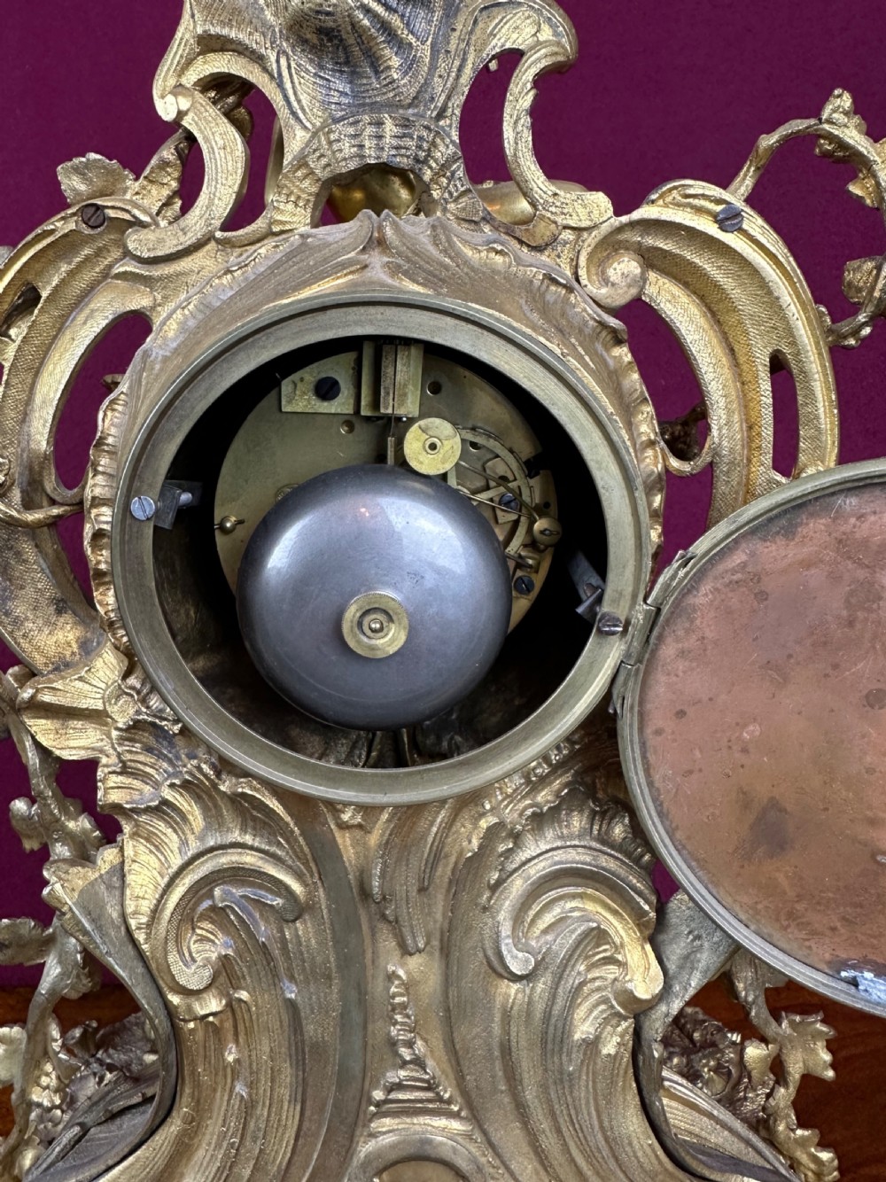 An ornate 19th-century French gilt bronze mantel clock featuring sculptural cherubs, grapevine garlands, and an enamel Roman numeral dial face. View III