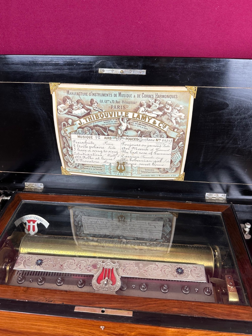 A rectangular Victorian wooden music box featuring floral iris marquetry inlaid on the lid with ebonised moulded borders. View III