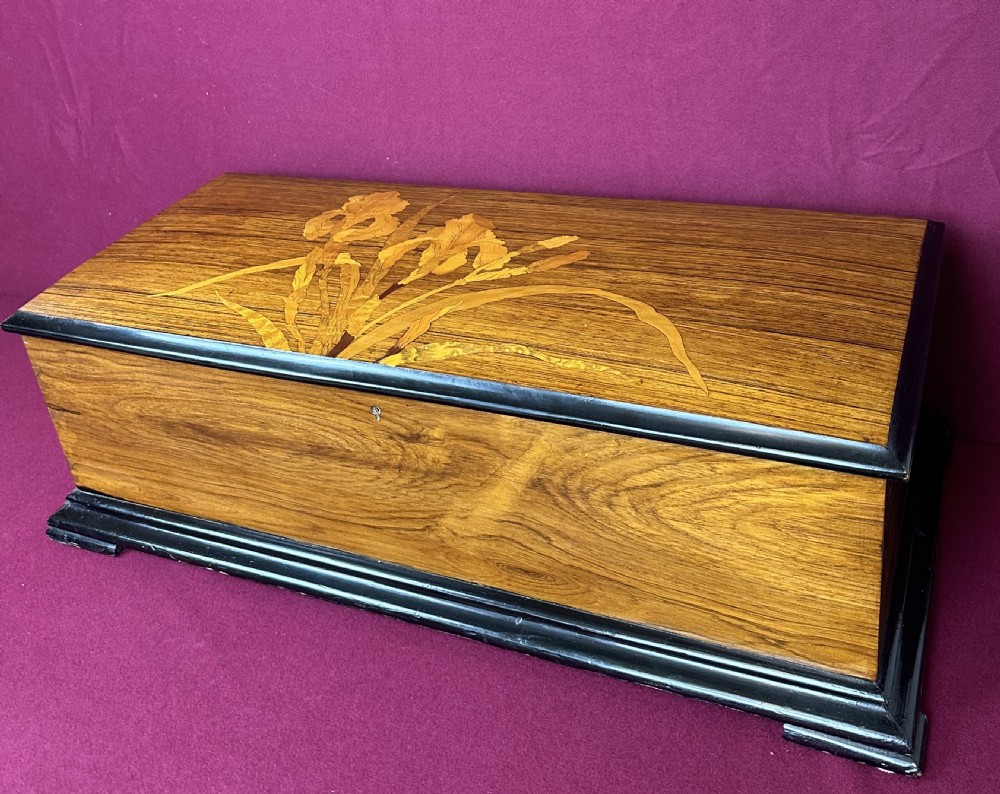 A rectangular Victorian wooden music box featuring floral iris marquetry inlaid on the lid with ebonised moulded borders. View VI