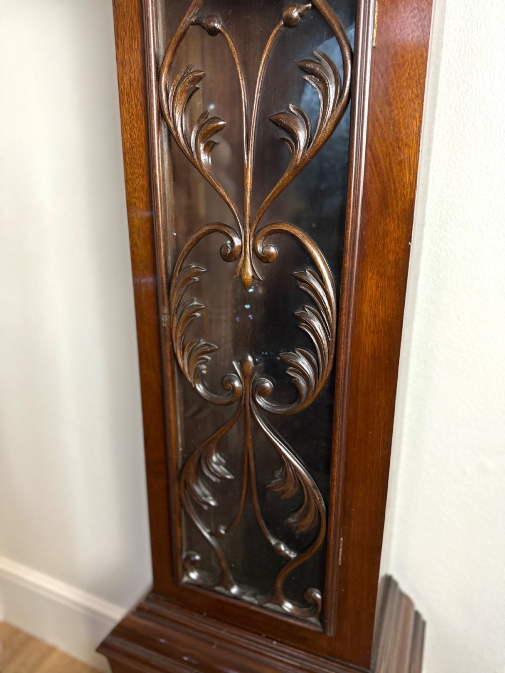 A carved mahogany longcase clock featuring an ornate brass dial, scrolled pediment with a Tempus Fugit plaque, and decorative wood tracery glass panel. View VI