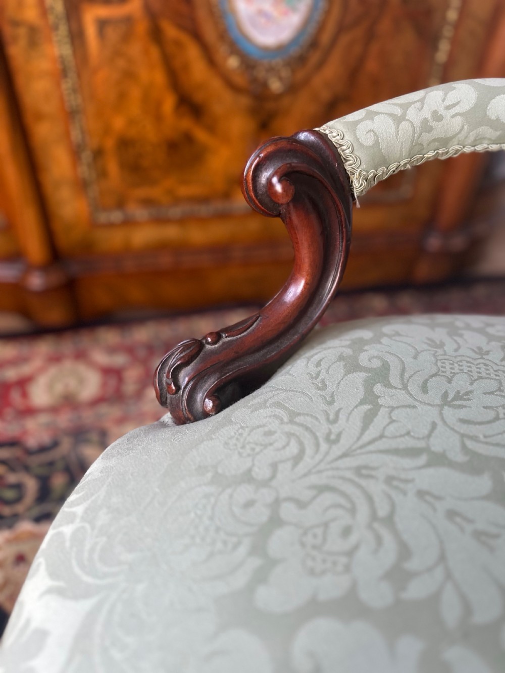 A pair of late Victorian carved mahogany salon armchairs upholstered in light green damask fabric featuring cabriole legs and scroll arms. View III