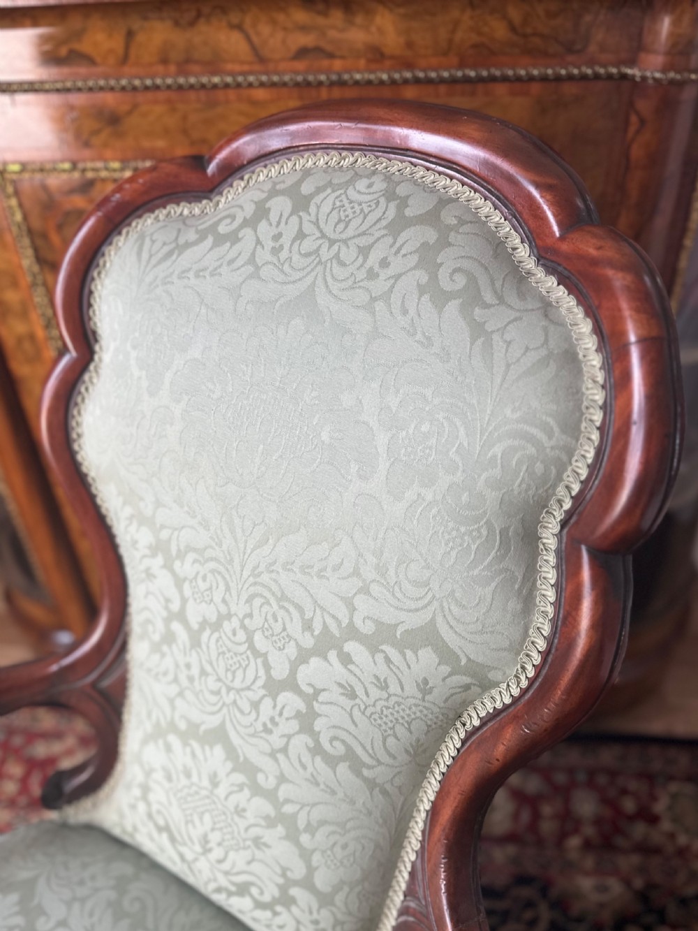 A pair of late Victorian carved mahogany salon armchairs upholstered in light green damask fabric featuring cabriole legs and scroll arms. View IV