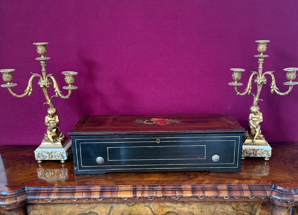 A Victorian rosewood cylinder music box featuring central floral marquetry inlay and an ebonised case with line stringing. View II