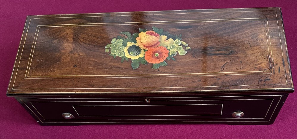 A Victorian rosewood cylinder music box featuring central floral marquetry inlay and an ebonised case with line stringing. View V