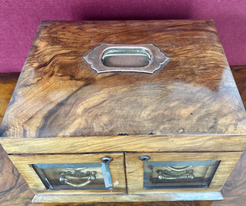 An open late Victorian walnut jewellery and sewing box featuring a green tufted silk lid lining with an oval mirror, top storage section, and two lower drawers behind glass doors. View VI