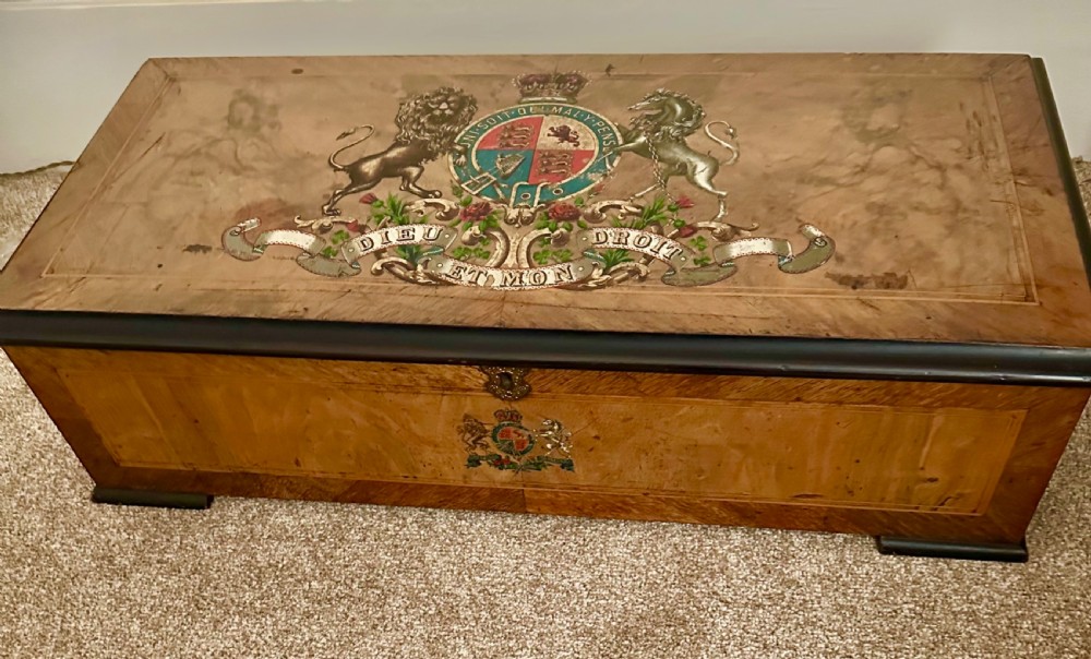 A Victorian burr walnut music box decorated with a painted British royal coat of arms on the top lid and front panel.