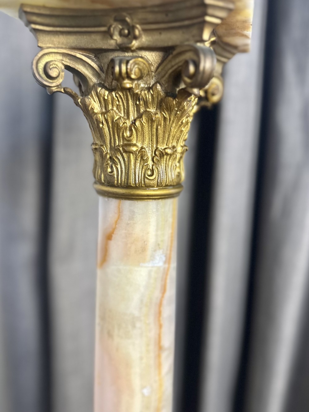 A tall cream-toned banded onyx column featuring a gilt bronze Corinthian capital, a square top plate, and a stepped square base. View IV