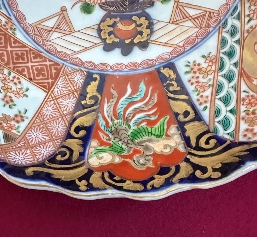 A pair of circular Japanese Imari porcelain chargers featuring scalloped edges, cobalt blue and iron-red painted panels, and central flower basket motifs with gilded accents. View III
