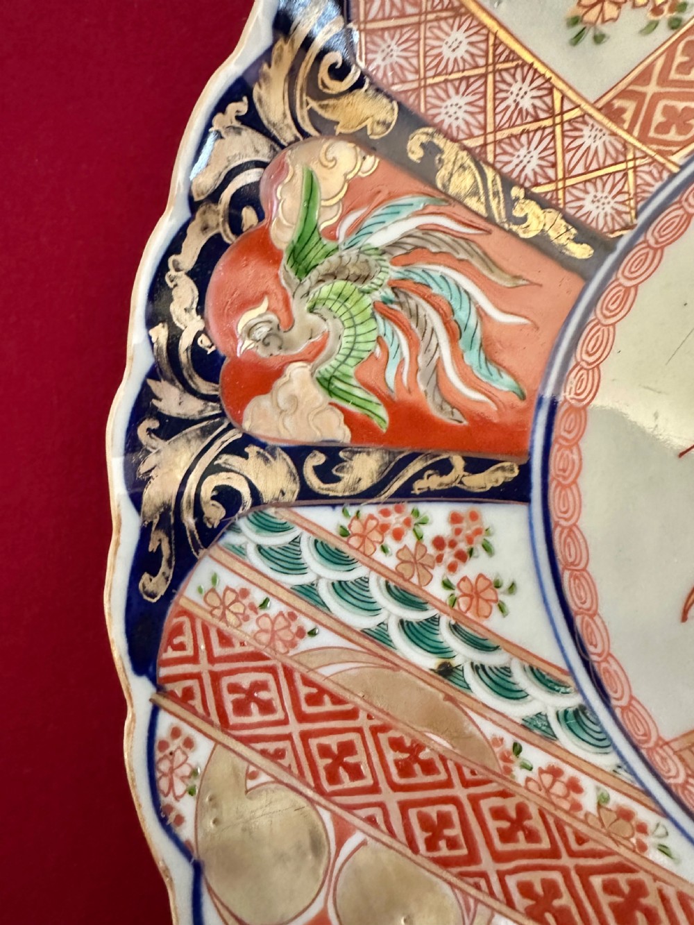 A pair of circular Japanese Imari porcelain chargers featuring scalloped edges, cobalt blue and iron-red painted panels, and central flower basket motifs with gilded accents. View VII
