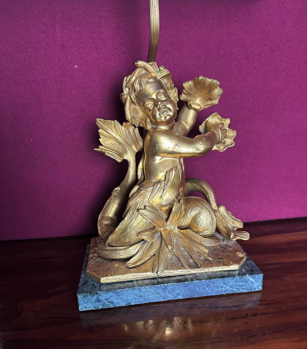 A pair of late nineteenth-century French ormolu table lamps featuring cast bronze cherub figures mounted on marble bases with soft pink fabric shades. View II