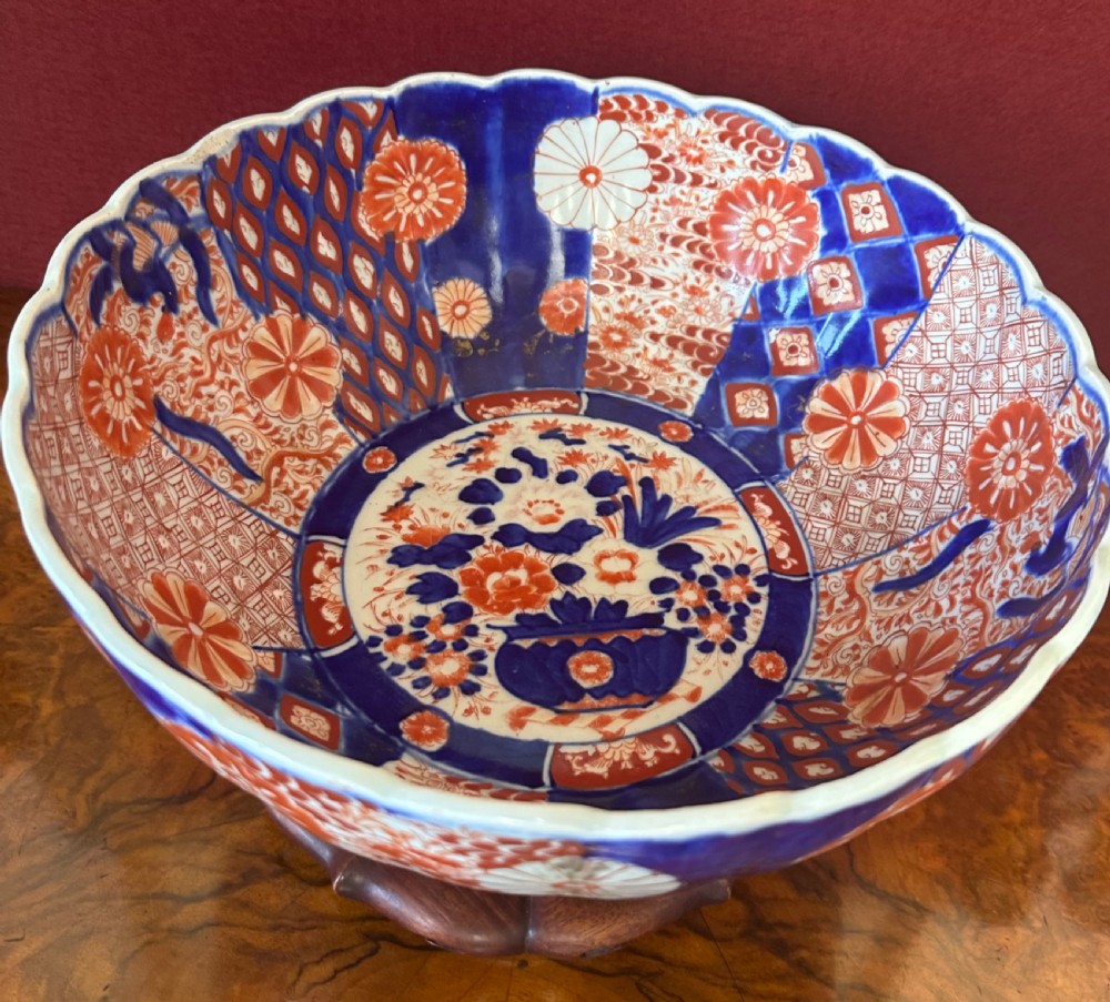 A fluted Japanese Imari porcelain bowl decorated with complex cobalt blue and iron red floral and geometric patterns.