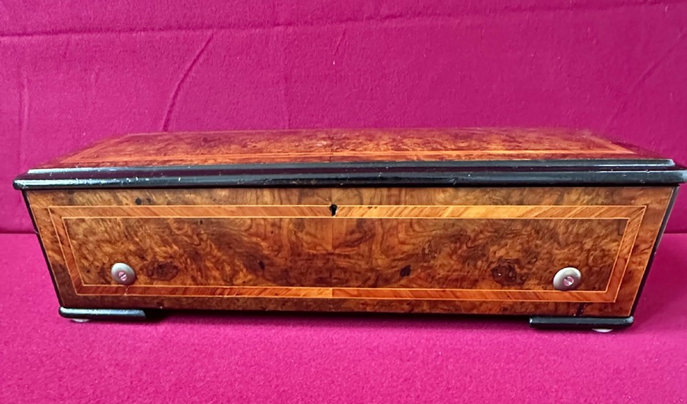A rectangular Victorian burr walnut cylinder music box featuring ebonised borders and boxwood inlay stringing. View VI