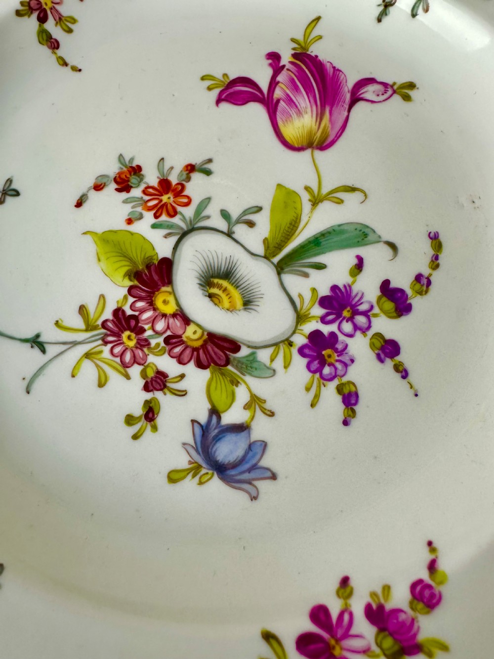 A pair of round white porcelain plates featuring hand-painted botanical flowers with scalloped edges. View II
