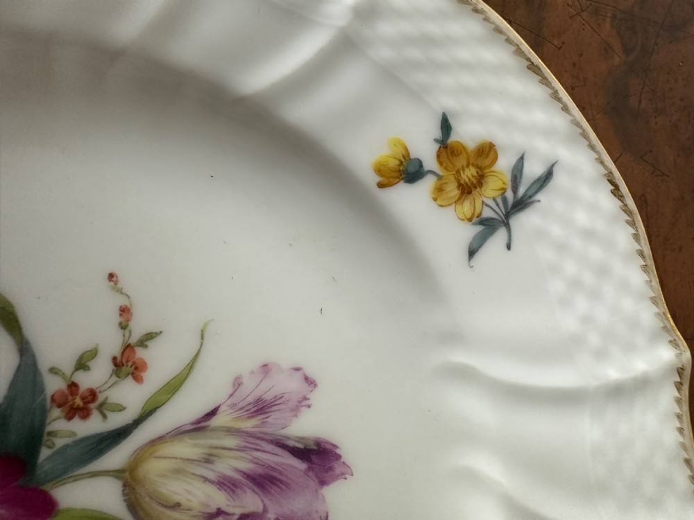 A pair of round white porcelain plates featuring hand-painted botanical flowers with scalloped edges. View IV