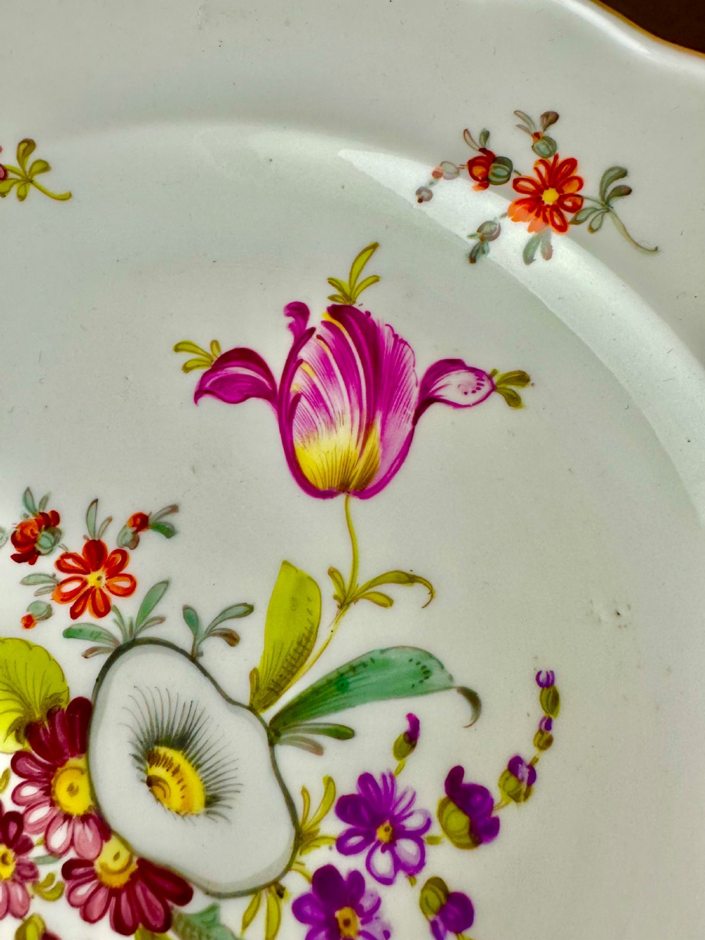A pair of round white porcelain plates featuring hand-painted botanical flowers with scalloped edges. View VI