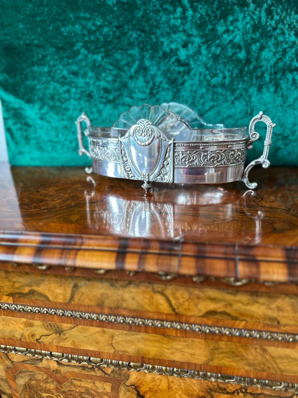 An oblong silver-plated Art Nouveau centrepiece bowl featuring ornate twin handles, relief scrollwork, a central cartouche, and a clear glass liner.