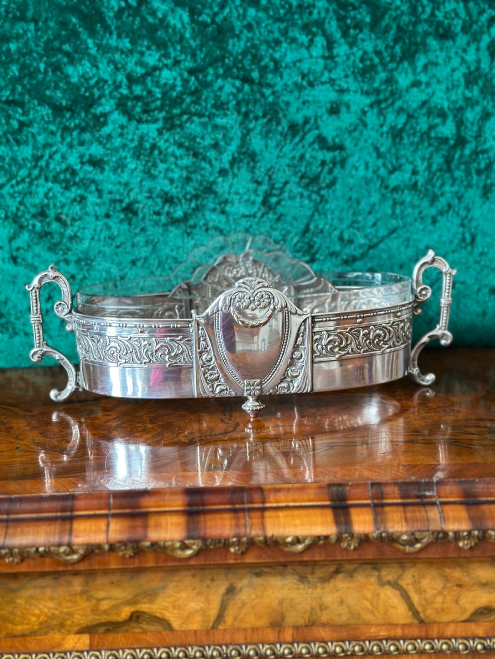 An oblong silver-plated Art Nouveau centrepiece bowl featuring ornate twin handles, relief scrollwork, a central cartouche, and a clear glass liner. View V