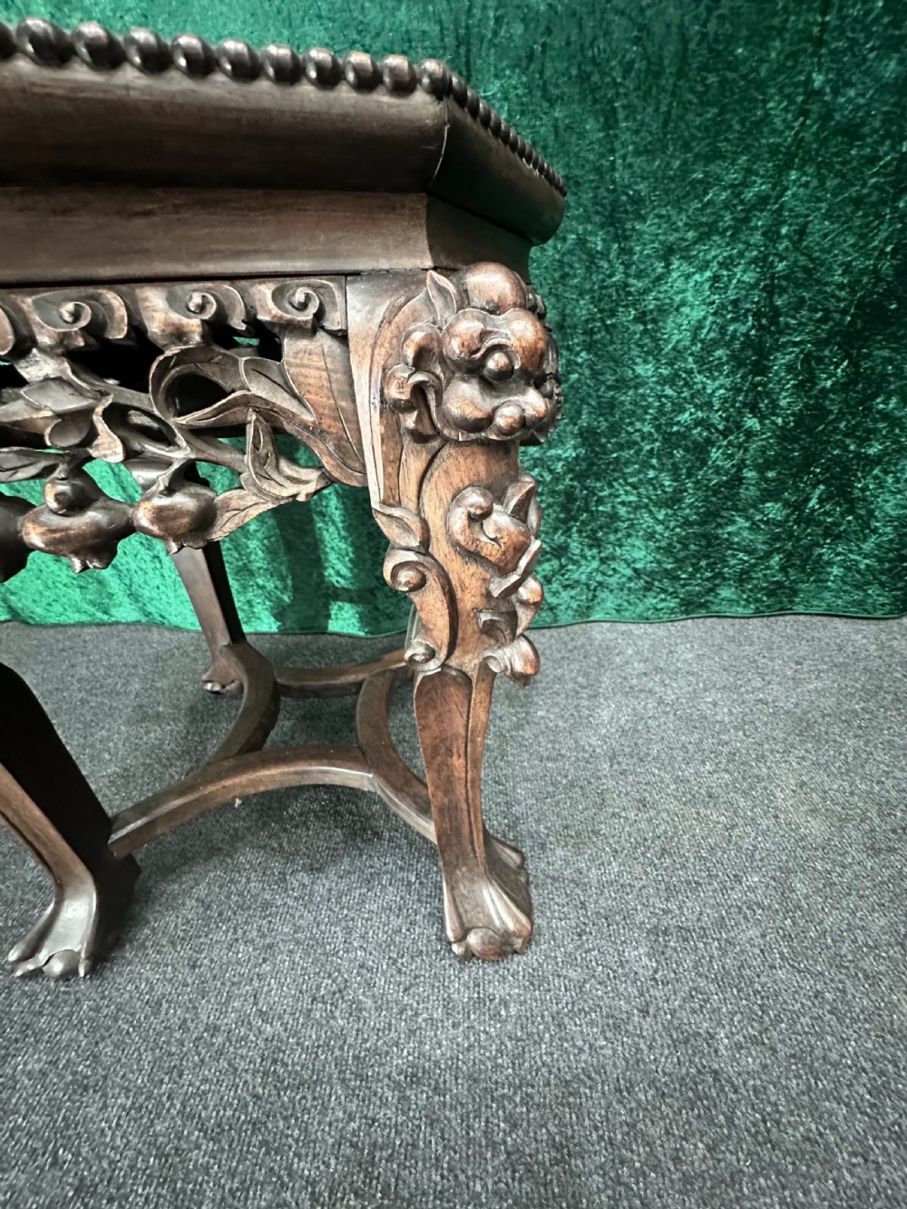 A dark carved padouk wood hexagonal stand featuring an inset marble top, pierced foliage apron, and cabriole legs. View V